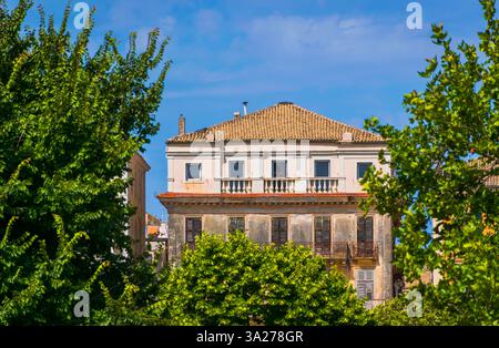 Vecchio edificio veneziano abbandonato che raggiunge il picco tra i vivaci alberi verdi della città di Corfù, in Grecia Foto Stock