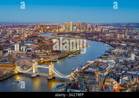 Il vibrante cielo serale proietta un bagliore dorato sul Tower Bridge mentre attraversa il Tamigi, evidenziando il vivace paesaggio urbano di Londra, Inghilterra, e il suo skyline. Foto Stock