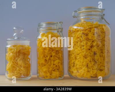 vasetti di vetro ripieni di pasta di diverse dimensioni su un tavolo di legno, primo piano Foto Stock
