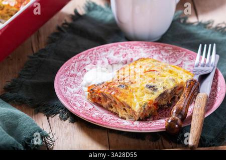 Omelette al forno con verdure servite con panna acida su sfondo di legno. Stile rustico, concentrazione selettiva. Foto Stock