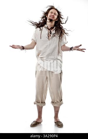Un uomo dai capelli lunghi con le braccia allungate, indossa un abbigliamento casual e aderente. Ha un'espressione gioiosa, che suggerisce un atteggiamento spensierato Foto Stock