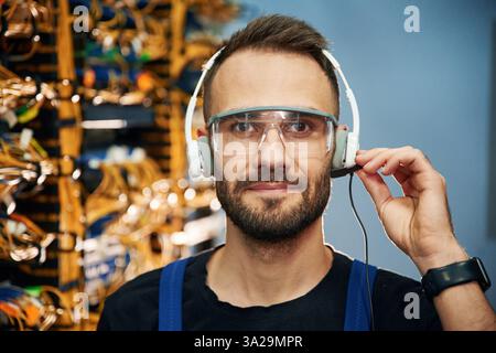 In cuffie. Il giovane lavora con apparecchiature Internet e cavi nella sala server. Foto Stock
