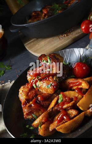 Ali di pollo rustiche in miele con zeppe di patate Foto Stock