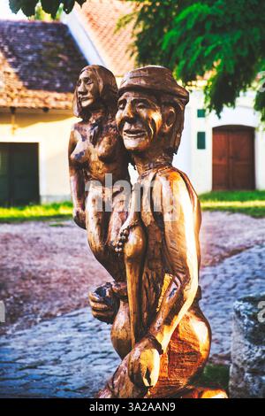 Una scultura in legno raffigurante una coppia sorridente, con l'uomo che tiene la donna sulla schiena. Le figure sono intagliate in modo complesso, mostrando dettagli in t Foto Stock