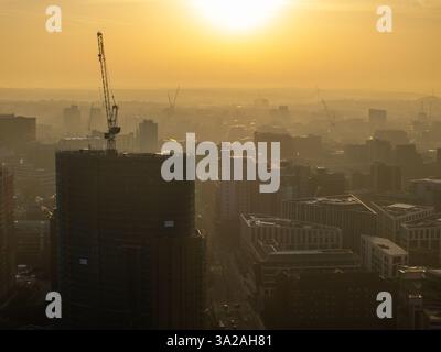 Una vista sopraelevata del centro di Leeds durante l'alba, evidenziando l'attività di costruzione nel mezzo dello skyline urbano sotto un'alba dorata. Foto Stock