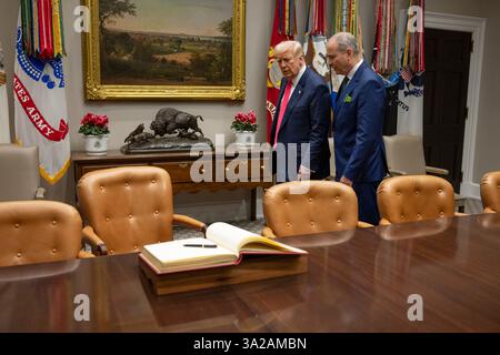 Washington, Stati Uniti. 12 marzo 2025. U. Il presidente Donald Trump, a sinistra, cammina con il Taoiseach irlandese Micheal Martin, a destra, per firmare il libro degli ospiti durante la tradizionale visita del giorno di San Patrizio presso la Cabinet Room della Casa Bianca, 12 marzo 2025 a Washington, DC Credit: Daniel Torok/White House Photo/Alamy Live News Foto Stock