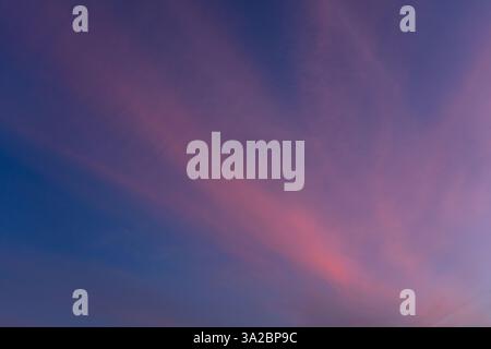 Il crepuscolo si deposita all'orizzonte, generando splendide sfumature di rosa e viola attraverso il cielo. Le nuvole morbide creano un'atmosfera serena perfetta anche per te Foto Stock