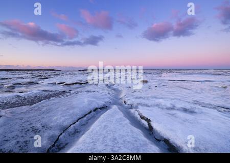 Un paesaggio invernale ghiacciato del Waddenzee nei Paesi Bassi con piattaforme ghiacciate e linee principali e un bel cielo - un freddo paesaggio invernale Foto Stock