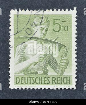 Francobollo cancellato stampato dalla Germania, Realm, che mostra i lavoratori in servizio, 8 anni di impegno lavorativo, circa 1943. Foto Stock