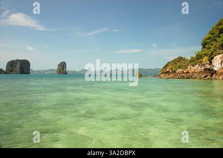 Le isole carsiche di pietra calcarea dell'isola di Hong si innalzano dalle acque turchesi del Mare delle Andamane sotto un cielo azzurro limpido nel sud della Thailandia Foto Stock