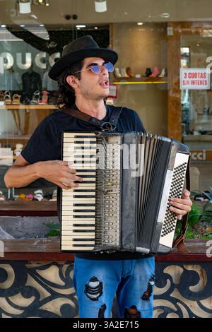Un musicista di strada o un ciclista che suona l'accordiano per consigli su una strada a Santiago del estero, Argentina. Foto Stock