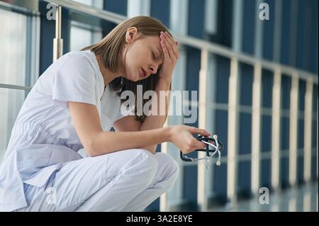 Stanco, sentimento cattivo, esausto. Medico donna in giacca bianca e' nel corridoio. Foto Stock