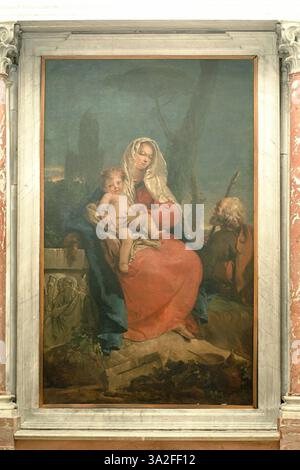 Il dipinto di Giovanni Battista Tiepolo del 1742-1745, Rest in the Flight to Egypt, ritrae la Sacra famiglia che riposa durante la loro fuga in Egitto. La composizione barocca trasmette tranquillità e devozione, con luci soffuse e figure dettagliate. Il dipinto è a Venezia, in Italia. Foto Stock