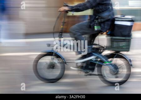 Motion Blur - il corriere di cibo giapponese attraversa la città di Nagoya su una piccola bicicletta motorizzata dotata di un grande cesto montato sul retro. Foto Stock