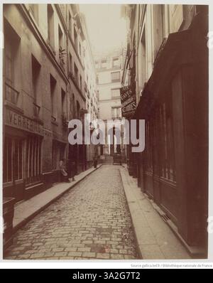 La fotografia di Rue de l'Hirondelle di Eugène Atget cattura il fascino suggestivo di questo storico vicolo parigino, che conduce alla Cour de l'Hôtel de la Salamandre. La foto sottolinea la bellezza tranquilla dello spazio urbano, mostrando l'ambiente architettonico circostante. Foto Stock