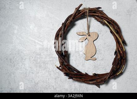 corona pasquale di rami di viti con coniglio su sfondo grigio con imitazione. decorazione Foto Stock
