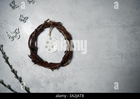 corona pasquale di rami di viti con filetto su sfondo grigio con copyspace. decorazione con uova Foto Stock