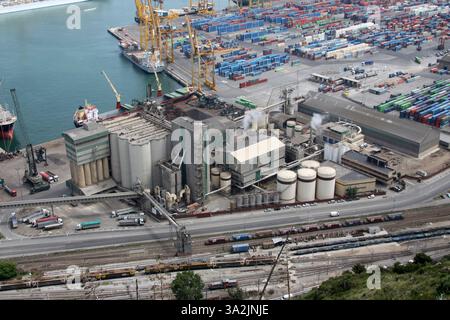 Porto affollato con navi da carico e un grande complesso industriale. Vista ad alto angolo, operazioni logistiche e colori disattivati Foto Stock