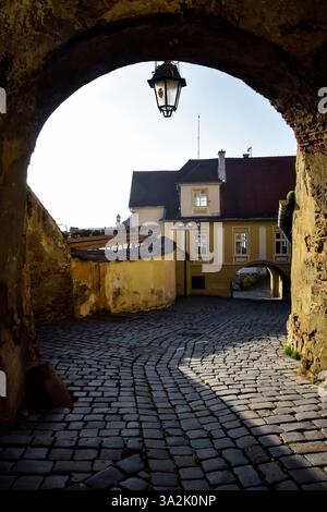 Passaggio ad arco con lanterna su un'antica strada acciottolata nell'antica città europea. Foto Stock