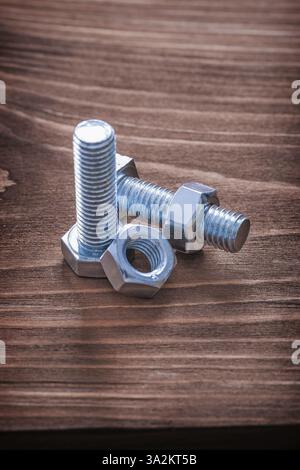 Bulloni e dadi in acciaio inox su tavola di legno marrone concetto di costruzione Foto Stock