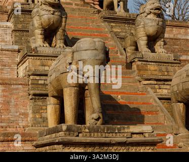 Bhaktapur, Nepal - 10 febbraio 2025 - elefante e cane scolpito in pietra sui gradini che portano ad un Tempio buddista Piazza Dunbar Foto Stock