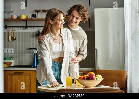 Le giovani coppie si divertono a vicenda mentre preparano un pasto nella loro cucina moderna e accogliente. Foto Stock
