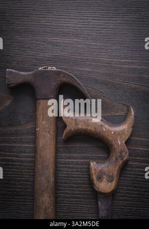 Sega a mano e martello da artiglio arrugginiti su sfondo in legno vintage Foto Stock