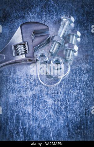 Chiave regolabile in acciaio, rondelle, dadi a vite e viti filettate su fondo metallico graffiato Foto Stock