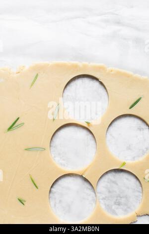 Vista dall'alto di tagliare l'impasto dei biscotti allo zucchero al rosmarino, l'impasto dei biscotti alle erbe e il processo di preparazione dei biscotti allo zucchero Foto Stock