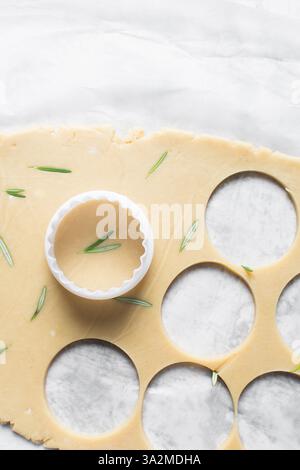 Vista dall'alto di tagliare l'impasto dei biscotti allo zucchero al rosmarino, l'impasto dei biscotti alle erbe e il processo di preparazione dei biscotti allo zucchero Foto Stock