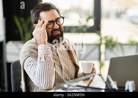 Il bell'anziano sorseggia il caffè in uno spazio di lavoro luminoso e moderno. Foto Stock