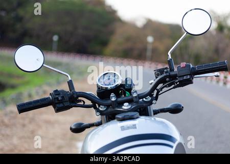 Manubrio, specchietti e vista tachimetro della motocicletta. Vista sulla strada da una motocicletta d'epoca. Sfondo a tema bici. Foto Stock
