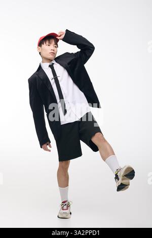 Un giovane uomo asiatico alla moda si mette in posa con fiducia, mescolando moda e carisma. Foto Stock