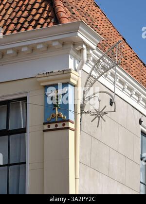 6 marzo 2025 - Dokkum, Paesi Bassi: Una storica pietra della facciata con un design medico su un edificio bianco a Klein Diep a Dokkum, sotto un cielo azzurro Foto Stock