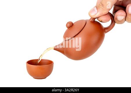Versare il tè da una tradizionale teiera cinese in argilla color mattoni. Foto Stock