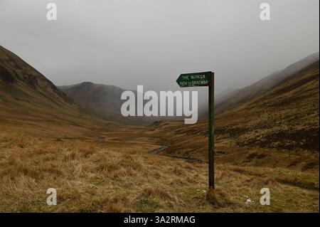 Un cartello "Monega Path to Braemar" nella valle di Caenlochan alla testa di Glenisla, come un fronte di slittino emerge dalla valle di Canness ad Angus, in Scozia. Foto Stock