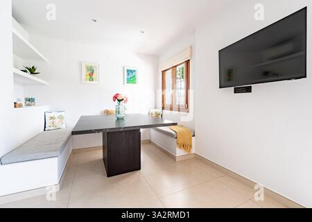 un'immagine di una piccola area da pranzo con televisione montata a parete nell'appartamento di vacanza Foto Stock