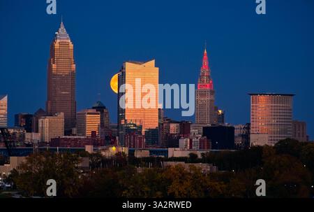 La luna piena che si innalza sopra Cleveland, Ohio, il 17 settembre 2024, sembra salire sul lato di uno dei grattacieli della città. Foto Stock