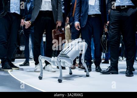 Un cane robot che cammina e gioca intorno alle persone in una fiera tecnologica. Concetto di innovazione ingegneristica robotica e intelligenza artificiale ai Foto Stock