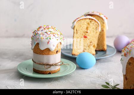 Piatti con dolci torte di Pasqua e uova dipinte su un tavolo grigio Foto Stock