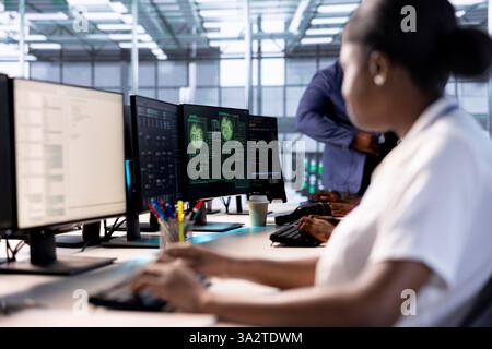 Computer scientist riconfigurazione server farm per ottimizzarla in base alle esigenze di elaborazione dei dati dei clienti. Donna afroamericana che lavora per garantire il funzionamento efficiente delle apparecchiature dei data center Foto Stock