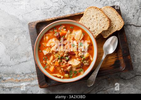 Zuppa invernale di pomodoro con cavolo di manzo macinato e verdure in primo piano in una ciotola sul tavolo. Vista dall'alto orizzontale Foto Stock