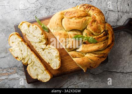 Primo piano della treccia di pane al pesto fatto in casa all'italiana su una tavola di legno sul tavolo. Vista dall'alto orizzontale Foto Stock
