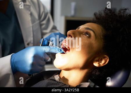 Dentista professionista che esamina un paziente in una moderna clinica dentale Foto Stock