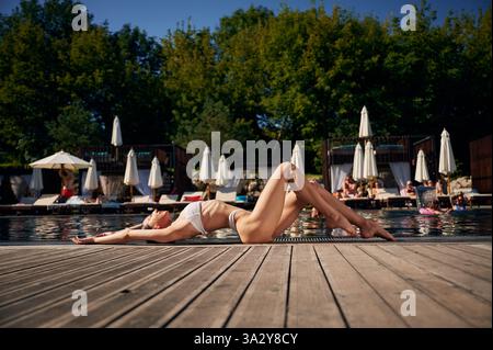 Vista laterale, posizionamento. Donna in bikini bianco è vicino alla piscina. Foto Stock