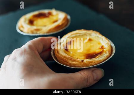 Mano che regge un delizioso pastel de nata, invitante dolce Foto Stock