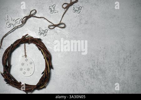 corona pasquale di rami di viti con filetto su sfondo grigio con copyspace. decorazione con uova Foto Stock