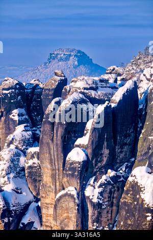 Paesaggio invernale innevato nel Parco Nazionale della Svizzera sassone con la formazione rocciosa Torsteine e la formazione rocciosa Lilienstein nel dista Foto Stock