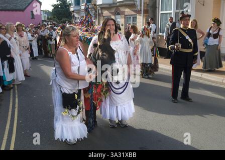 Dare la caccia al Conte di Rone. Le due assistenti donne che si occupano dell'asino durante l'annuale festival folcloristico. Folle di abitanti del villaggio che partecipano all'evento annuale. Combe Martin, Mid Devon Inghilterra, maggio 2011 UK 2010s HOMER SYKES. Foto Stock
