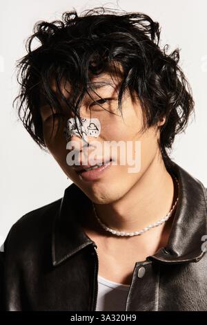 Giovane e alla moda uomo asiatico si mette in posa elegante in un ambiente bianco da studio. Foto Stock
